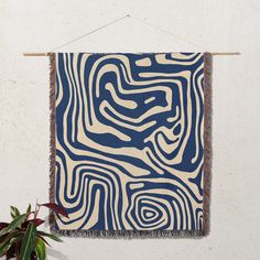 a blue and white tapestry hanging on a wall next to a potted green plant