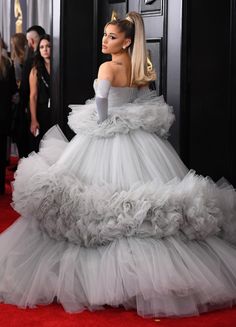 lady in white gown on red carpet with other people behind her wearing black and white