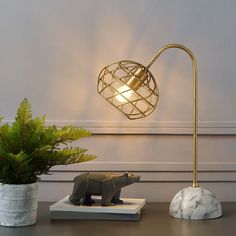 a table lamp with a bear figurine on it next to a potted plant