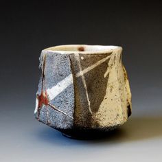 a white and black ceramic cup with designs on it's sides, sitting on a gray surface