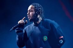 a man with dreadlocks holding a microphone in his right hand and wearing a black sweatshirt