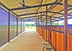 the inside of a covered area with benches and fencing on both sides of the walkway