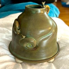 a green vase sitting on top of a bed