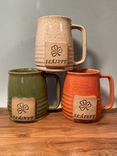 three ceramic mugs sitting on top of a wooden table