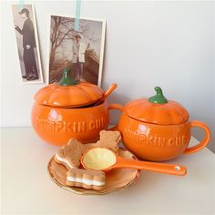 two orange pumpkin shaped dishes with matching serving platters and pictures on the wall behind them