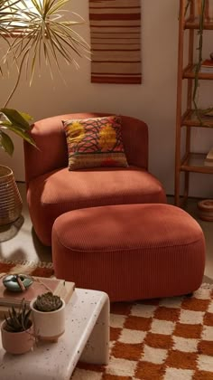 an orange chair and ottoman in a living room with potted plants on the floor