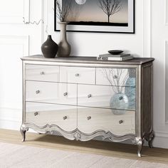 a silver and white dresser with two vases sitting on it's sideboard