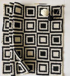 a black and white crocheted blanket with a ball of yarn sitting on top of it