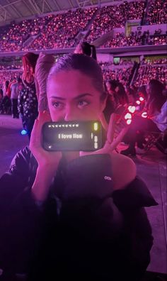 a woman taking a photo with her cell phone in front of an audience at a sporting event