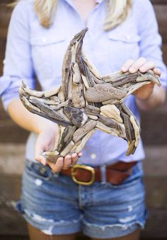 a woman holding up a piece of driftwood in her hands with the other hand