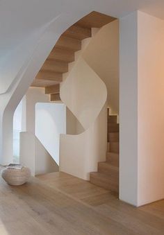 the interior of a modern house with wood flooring and white walls, staircase leading to another room