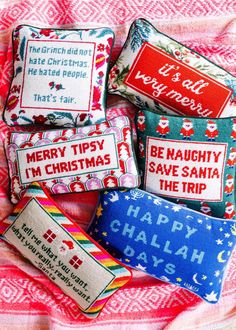 four pillows with different sayings on them sitting on a pink and white bed sheet