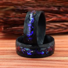 two black rings with purple and blue glitters on them sitting on a wooden surface