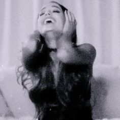 a woman sitting on top of a couch with her hands in the air and smiling