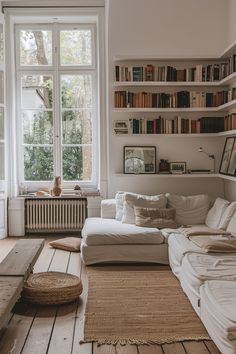 a living room filled with lots of furniture and bookshelves next to a window