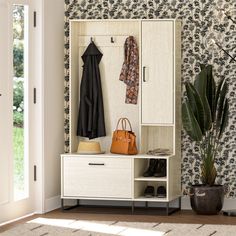 a coat rack with shoes and purses on it next to a potted plant