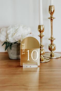 a table with two candles and a card holder on it next to a flower vase