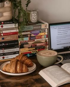 a laptop computer sitting on top of a desk next to a plate of croissants