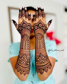 a woman holding her hands up with henna on it