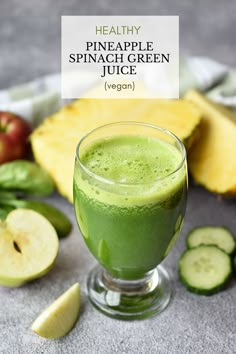 a green smoothie in a glass next to sliced fruit