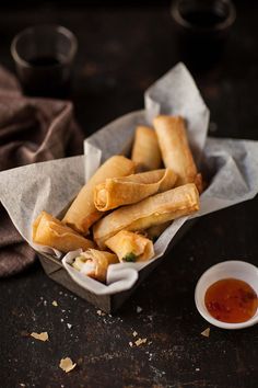 some food is sitting in a basket next to a small bowl with dipping sauce on the side