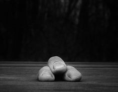 black and white photograph of three rocks stacked on top of each other in front of a dark background