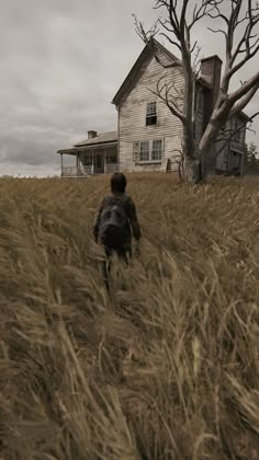 a person walking through tall grass towards a house