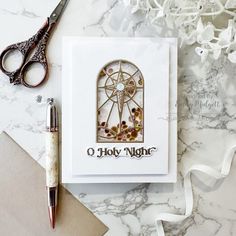 a card with a stained glass window on it next to a pair of scissors and a pen