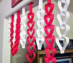 some red and white paper hearts hanging from the ceiling in front of a computer desk