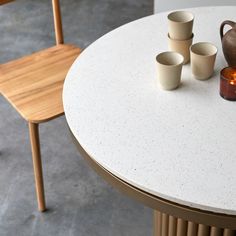 a table with four cups on it and a vase sitting next to the cup holder