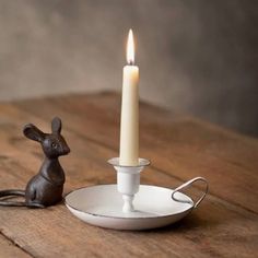 a candle is sitting on a plate with a mouse figurine next to it