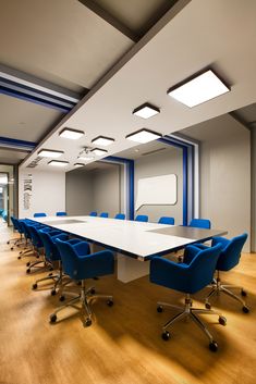 an empty conference room with blue chairs and a large white table in the middle of it