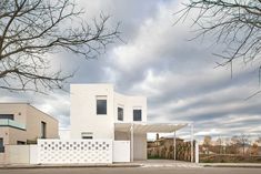 a white house sitting on the side of a road next to a tree and fence