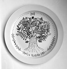 a white plate with an image of a tree on the front and bottom, in black ink