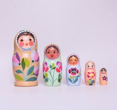 five wooden russian nesting dolls lined up against a white background with flowers and leaves painted on them