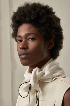 a woman with an afro is wearing a white shirt and black tie on her neck