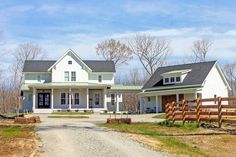 a large white house sitting on the side of a road next to a dirt road