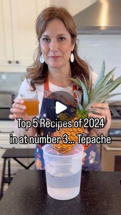 a woman holding a pineapple next to a cup