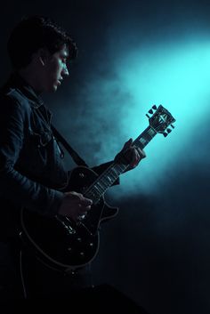 a man playing an electric guitar in the dark