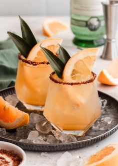 two glasses filled with orange margaritas and garnish