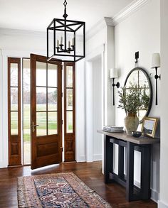 a foyer with a large rug, mirror and lantern light hanging from the ceiling above it