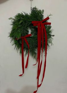 a christmas wreath hanging on the wall with red ribbon