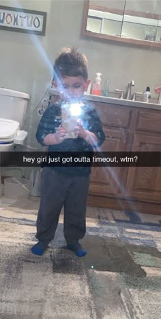 a young boy standing in front of a bathroom mirror holding a light up to his face