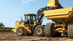 a large yellow dump truck parked on top of a dirt field