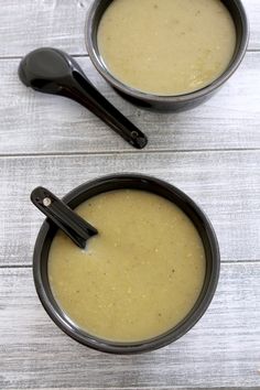 two bowls filled with soup sitting on top of a wooden table