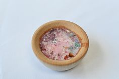 a small wooden bowl filled with lots of different colored stuff on top of a white table