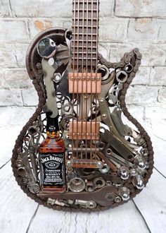 a miniature guitar made out of metal parts with a bottle of whiskey in the middle