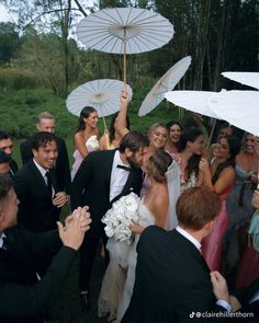 a group of people standing around each other with umbrellas over their heads in the air