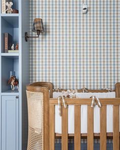 a baby's room with a blue bookcase and wooden crib in the corner