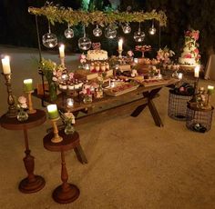 a table topped with lots of cakes and candles next to other desserts on top of wooden tables